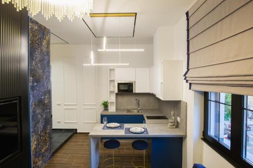 una cocina con armarios blancos y una isla azul en LIT Apartments, en Tirana