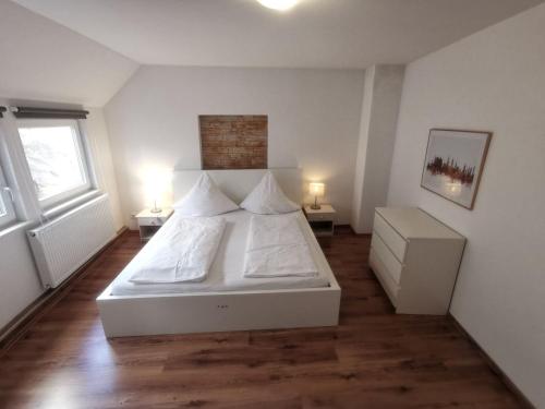 ハイデルベルクにあるFerienwohnungen Neckarblick - Heidelberg Altstadtのベッドルーム1室(白いベッド1台、テーブル2台、ランプ2つ付)