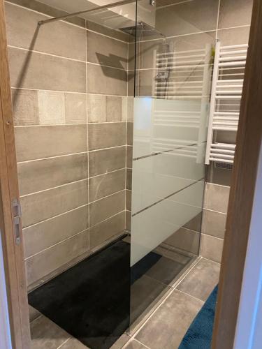 La salle de bains est pourvue d'une douche avec des portes en verre. dans l'établissement cottage Philippe et Valérie, à Silli-en-Gouffern