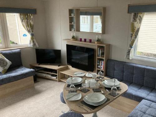 a living room with a table and a tv at Blackpool Static Caravan Marton Mere in Blackpool