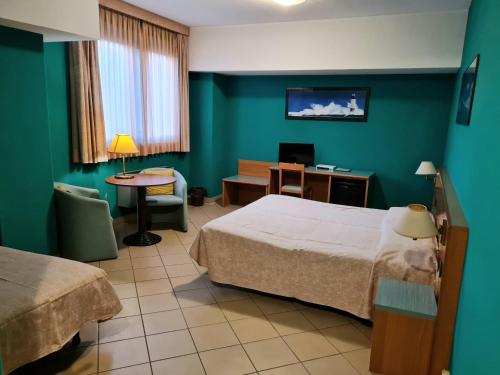 a hotel room with two beds and a desk and a table at Modo Hotel in Vercelli