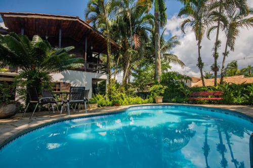 a swimming pool in front of a house with palm trees at Pousada Chalé Suíço in Paraty