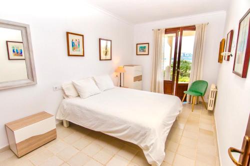 ein Schlafzimmer mit einem weißen Bett und einem grünen Stuhl in der Unterkunft CAN PERICÁS in Alcúdia