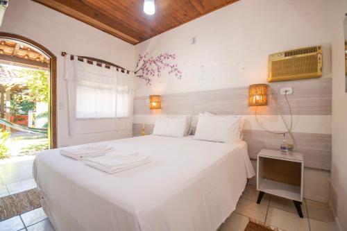 a bedroom with a large white bed and a window at Pousada Chalé Suíço in Paraty