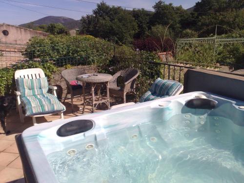 a hot tub on a patio with a table and chairs at L'Amandari - Chambres d'hôtes in Plan-de-la-Tour
