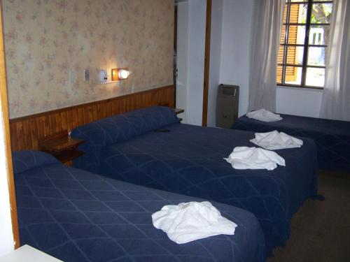 two beds in a hotel room with towels on them at Aloha in Villa Carlos Paz