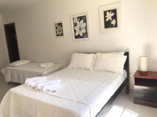 a bedroom with two beds with white sheets and a dresser at Pousada Sonho Meu in Itanhandu