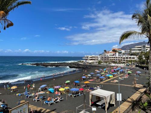 una playa con muchas sombrillas y gente en la playa en Apartamento Neptuno playa 17, en Puerto de Santiago