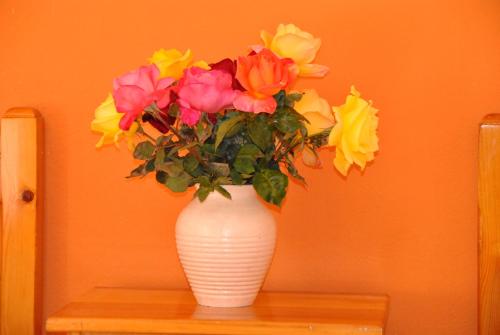 a white vase filled with colorful flowers on a table at Stergia Apartments in Kardamaina