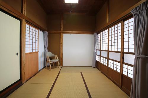 an empty room with a white door and windows at やどバーTATSUJi in Joetsu
