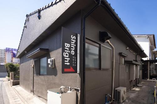 a building with a sign on the side of it at Guest House Shine Bright in Fukuoka