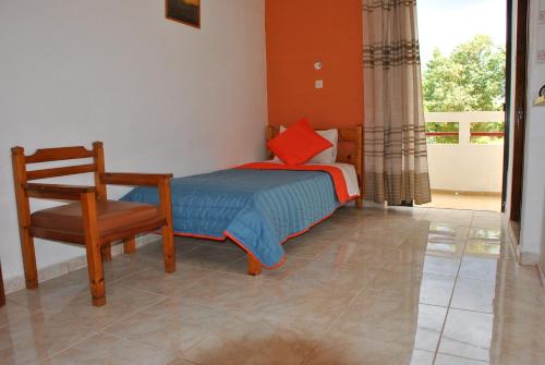 a bedroom with a bed and a chair and a window at Stergia Apartments in Kardamaina