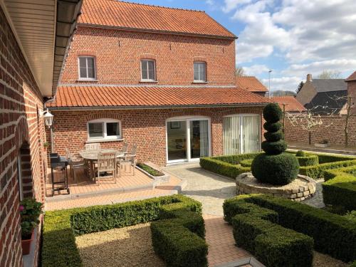 a brick house with a garden and a patio at Hoeve de Singel in Borgloon