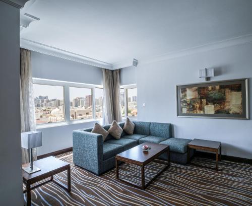 a living room with a blue couch and windows at Copthorne Downtown by Millennium in Abu Dhabi