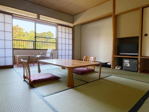 Zimmer mit einem Tisch, Stühlen und einem Fenster in der Unterkunft Miyajima Morinoyado in Miyajima