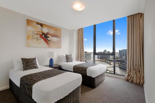 a hotel room with two beds and a large window at Jade Resorts Melbourne in Melbourne