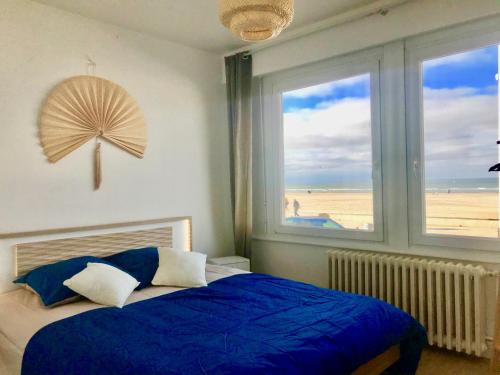 - une chambre avec un lit bleu et une vue sur la plage dans l'établissement Appartement VUE MER, à Dunkerque