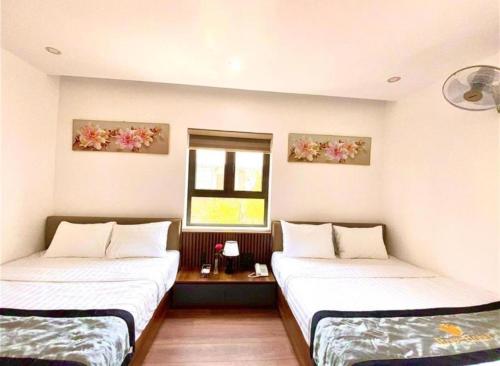 two beds in a room with a window at Rose Hotel Quảng Bình in Dong Hoi