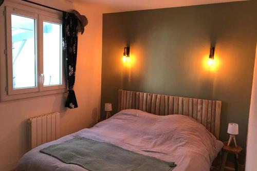 Ce lit se trouve dans une chambre dotée d'une fenêtre et de lumières. dans l'établissement Maison de vacances 2 chambres wifi à 400 m de la plage, à Les Moutiers