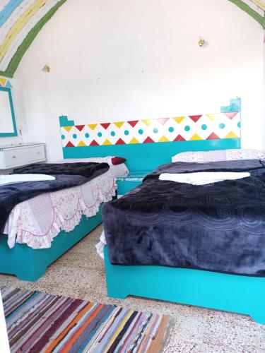 a bedroom with two beds and a colorful headboard at Baba Dool in Aswan