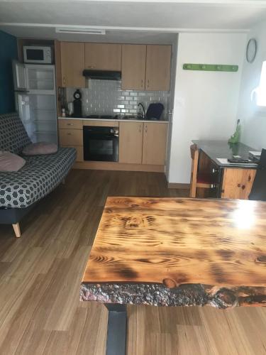 Il comprend un salon avec une table en bois et une cuisine. dans l'établissement Leucate, maison dans village naturiste Eden à 50 m de la plage, 4 personnes, à Leucate