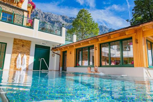 ein Paar im Swimmingpool eines Hauses in der Unterkunft Hotel Lindenhof in Ramsau am Dachstein