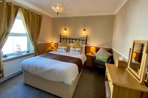 1 dormitorio con cama, escritorio y espejo en Sunny Bank Guest House, en Tenby