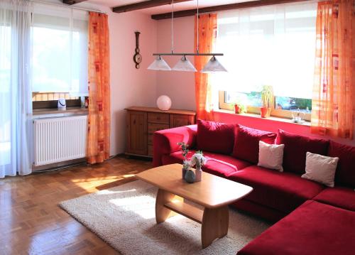 KemmernにあるFerienwohnung Schmetterlingのリビングルーム(赤いソファ、テーブル付)