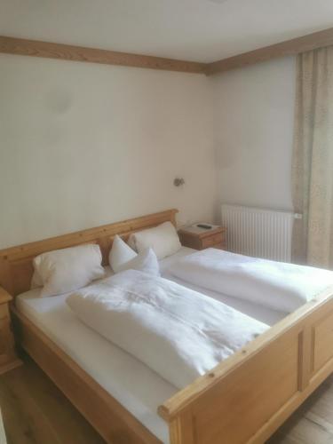 a bedroom with a large bed with white sheets at Gästehaus Obererlacher in Obertilliach