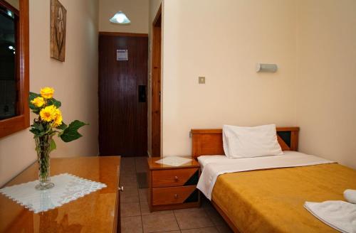 a bedroom with a bed and a vase of flowers on a table at Nicolas Hotel in Georgioupolis