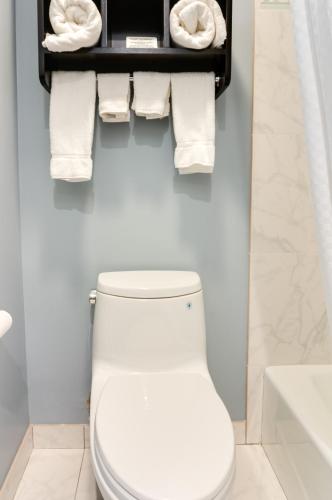 a bathroom with a toilet and towels on a shelf at Seaside Inn in San Francisco