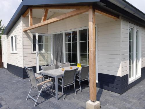 a patio with a table and chairs in front of a house at Nieuwe Beachbungalow aan IJsselmeer 39 24 four seasons in Lemmer