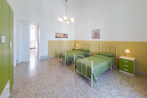 dwa łóżka w pokoju z zielonym i żółtym w obiekcie Casa Vacanze Penelope w mieście Alessano