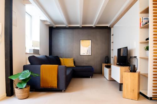 sala de estar con sofá azul y TV en homebydoni - Küche I Terrasse I 1000 Mbits WiFi I Design Loft nahe RMCC & Staatstheater, en Wiesbaden