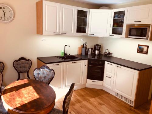 a kitchen with white cabinets and a table and a clock at Kohtu Apartment Unique in Kuressaare