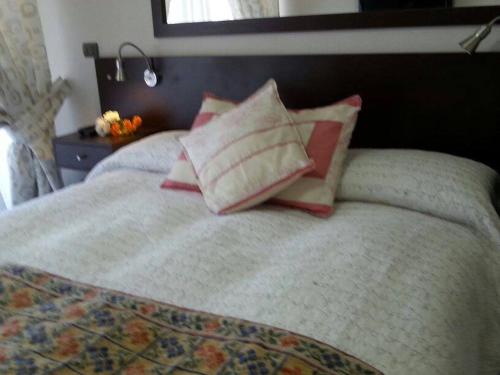 a bed with four pillows on top of it at Apart las Rastras talca in Talca