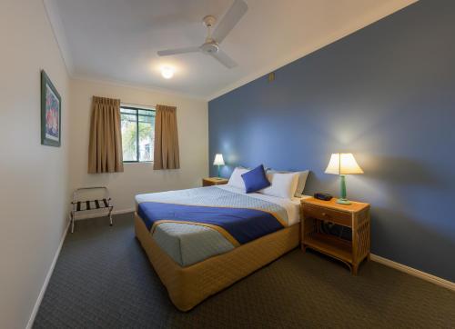 1 dormitorio con 1 cama con pared azul en Grosvenor in Cairns, en Cairns