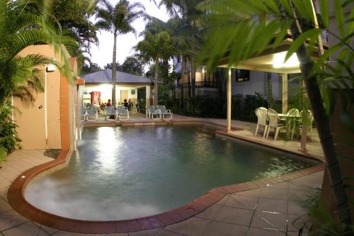 a swimming pool in a yard with chairs and tables at Grosvenor in Cairns in Cairns