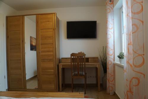 a room with a desk with a television and a mirror at Reethaus Casa Baltica in Börgerende-Rethwisch