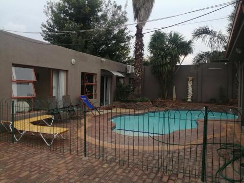 a swimming pool with chairs and a fence at Naisar's Apartments Primrose,Johannesburg in Johannesburg