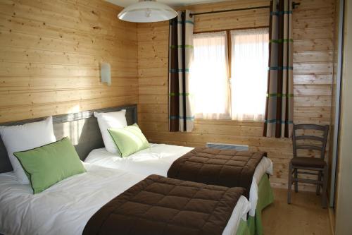 Un dormitorio con 2 camas y una silla. en Les Loges du Jura 4 étoiles, en Prénovel