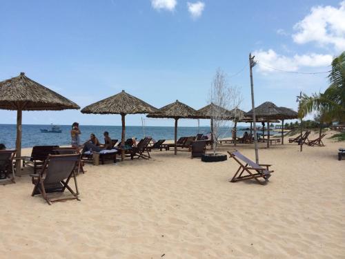 a group of people sitting under umbrellas on a beach at Thai Tan Tien Hotel in Phu Quoc