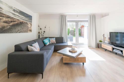 a living room with a couch and a tv at Vakantiehuis op Villapark Oesterbaai aan zee , met speeltuin grenzend aan de tuin in Wemeldinge