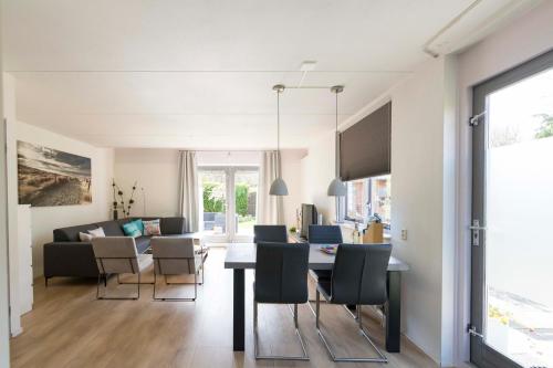 a dining room and living room with a table and chairs at Vakantiehuis op Villapark Oesterbaai aan zee , met speeltuin grenzend aan de tuin in Wemeldinge