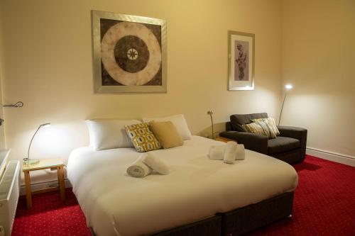 a bedroom with a large white bed and a chair at The Knighton Hotel in Knighton