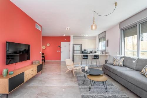 ein Wohnzimmer mit einem Sofa und einem TV in der Unterkunft 3 Bedrooms apt balcony & parking near banana beach in Tel Aviv