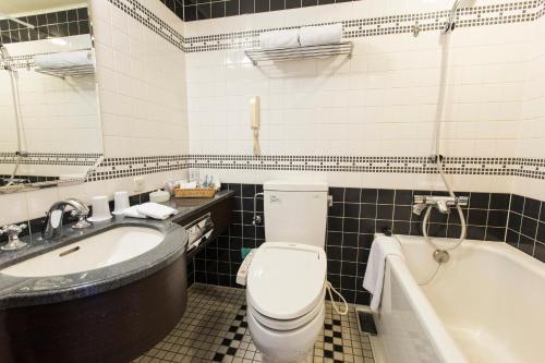 a bathroom with a toilet and a sink and a tub at Hotel Monterey Edelhof Sapporo in Sapporo