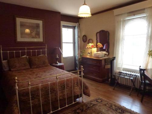 a bedroom with a bed and a dresser and windows at Auberge King Edward Bed and Breakfast in Ottawa