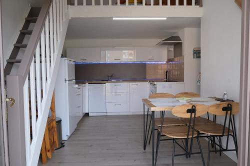 une cuisine avec des armoires blanches et une table et des chaises dans l'établissement La Grande Bleue, à Port-Leucate