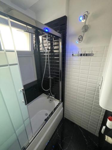 y baño con ducha y bañera con puerta de cristal. en Literie Haut de gamme entre gare et centre ville, en Dunkerque